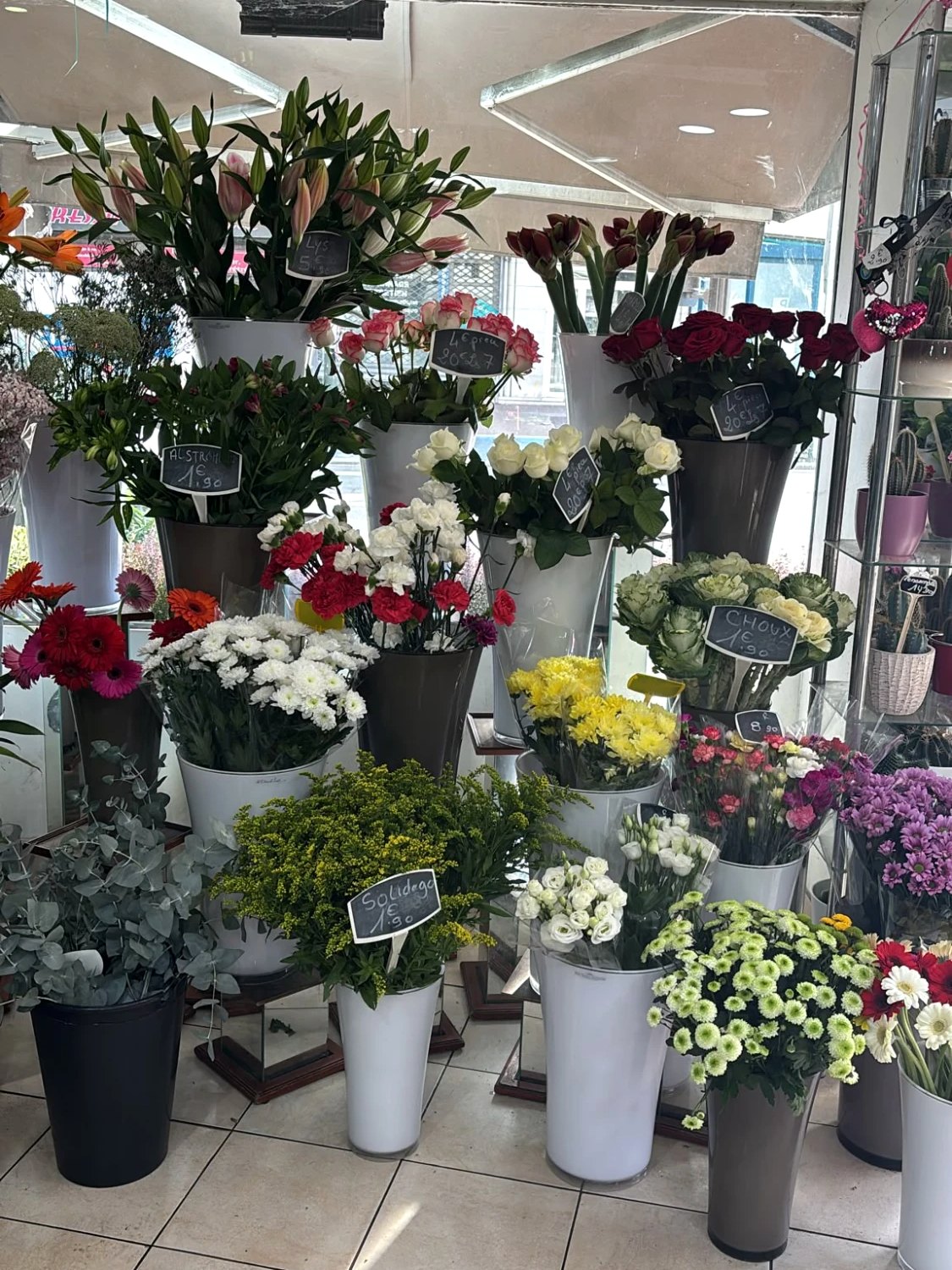 Les fleurs en vase dans la boutique&nbsp;: lys, amaryllis, roses, alstroemerias, œillets, chrysanthèmes, choux, solidago, lisianthus, gerberas et eucalyptus